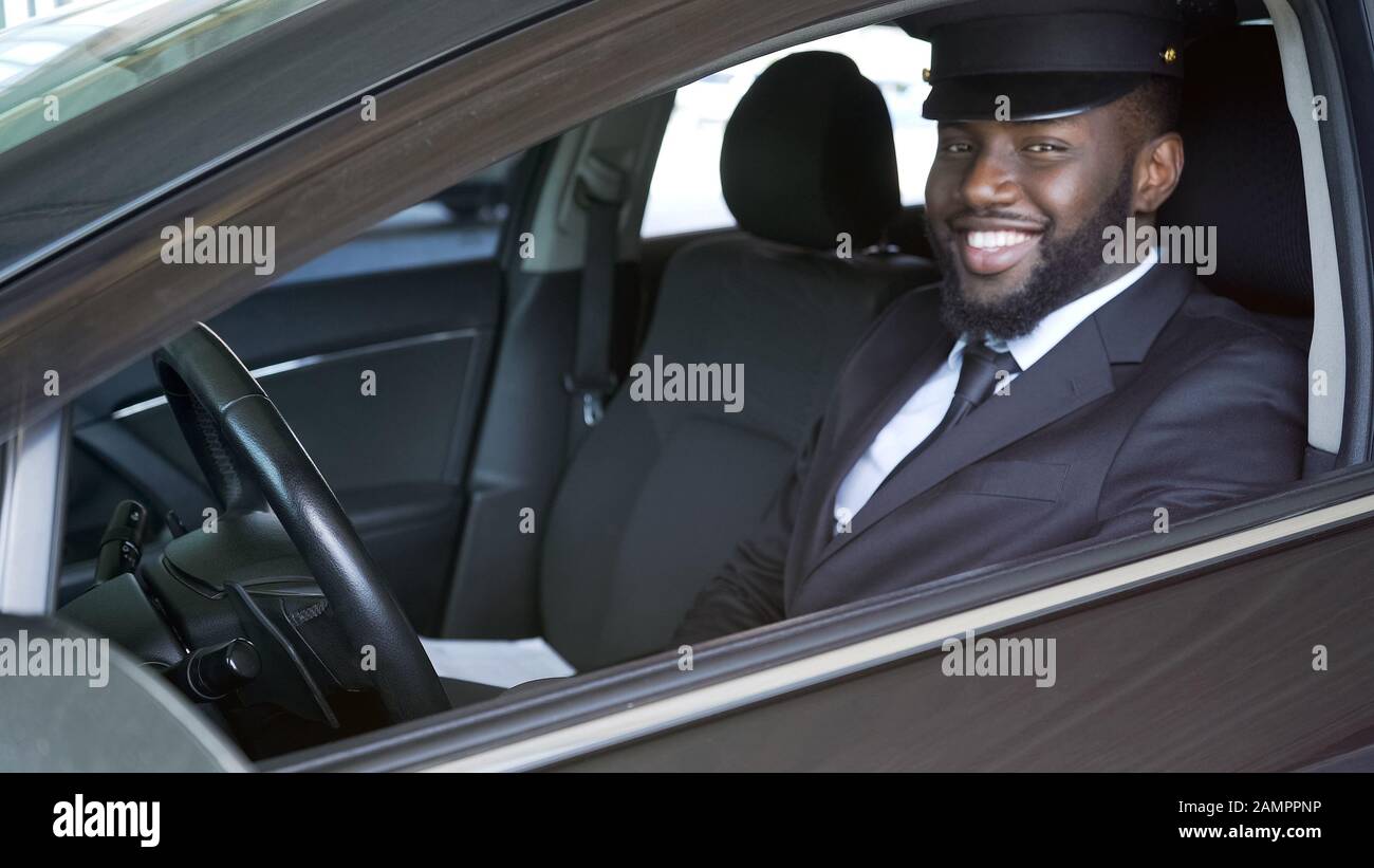 Happy African American chauffeur guardando in macchina fotografica, trasferimento di lusso, servizio Foto Stock