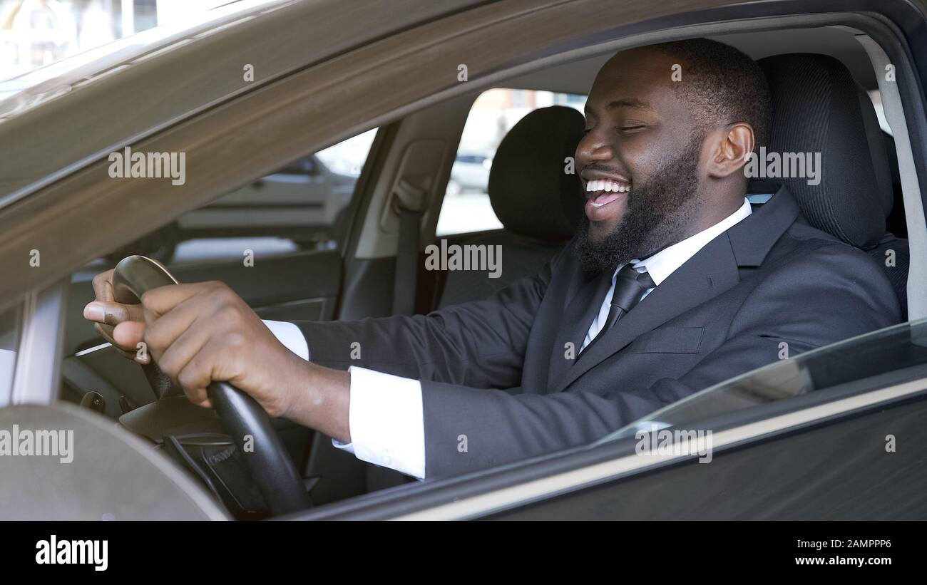 Allegro uomo d'affari nero seduto in automobile di lusso, prova su strada, trasporto Foto Stock