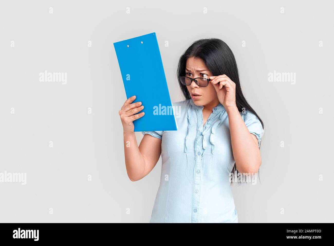 Stile Libero. Donna asiatica in occhiali in piedi isolato su bianco con appunti di controllo rapporto interessato Foto Stock