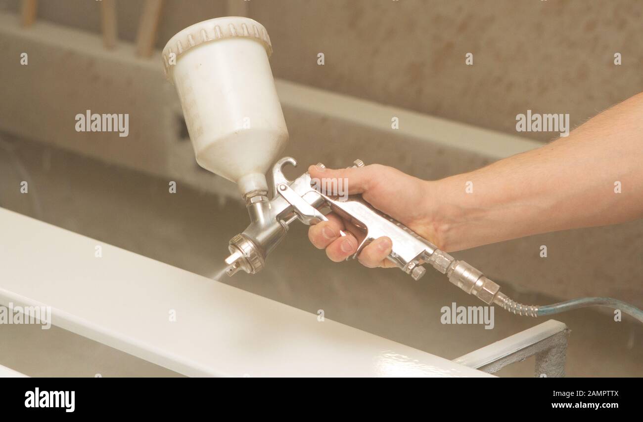 Un giovane pittore dipinge pezzi di legno per la produzione di mobili di legno, opera di un negozio di falegname Foto Stock