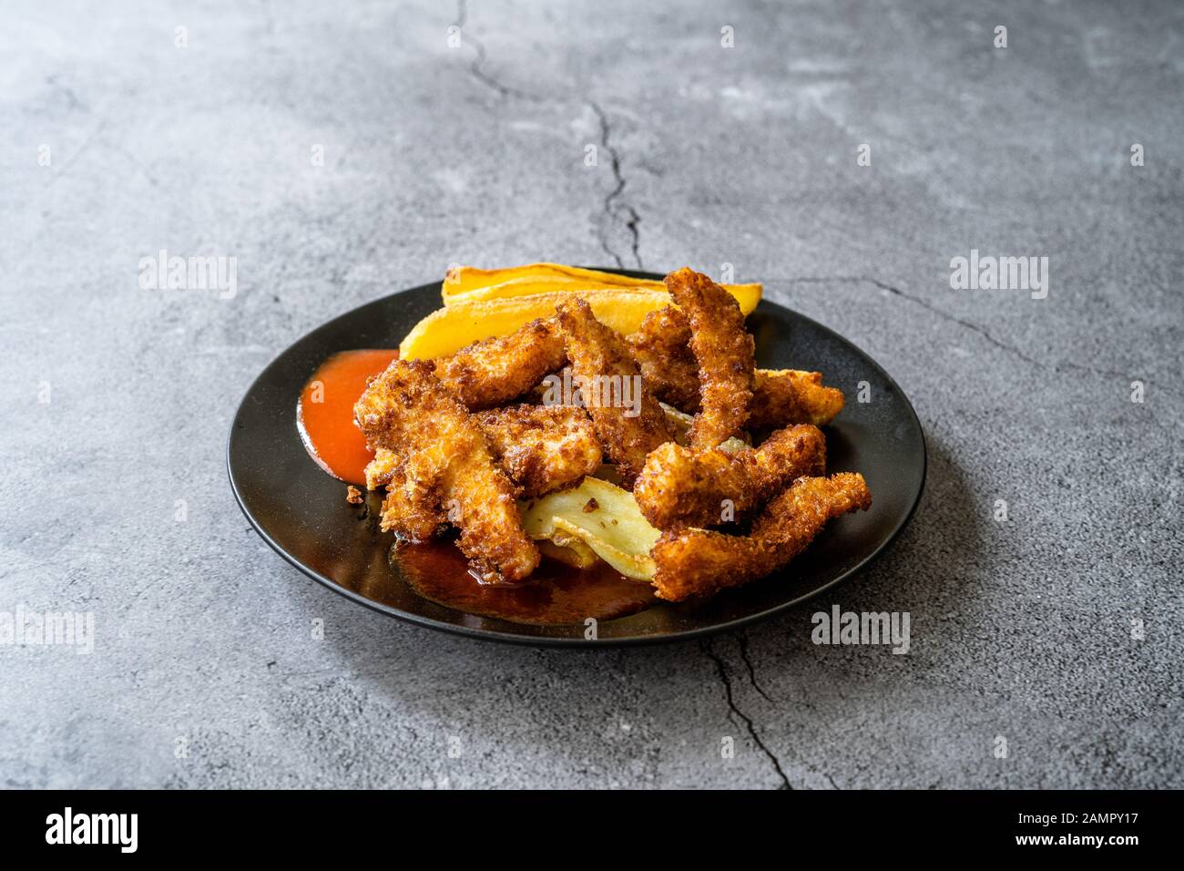 Pesce e Patatine fatte con il Bread e Fried Seabass in Black Plate. Fast Food. Foto Stock