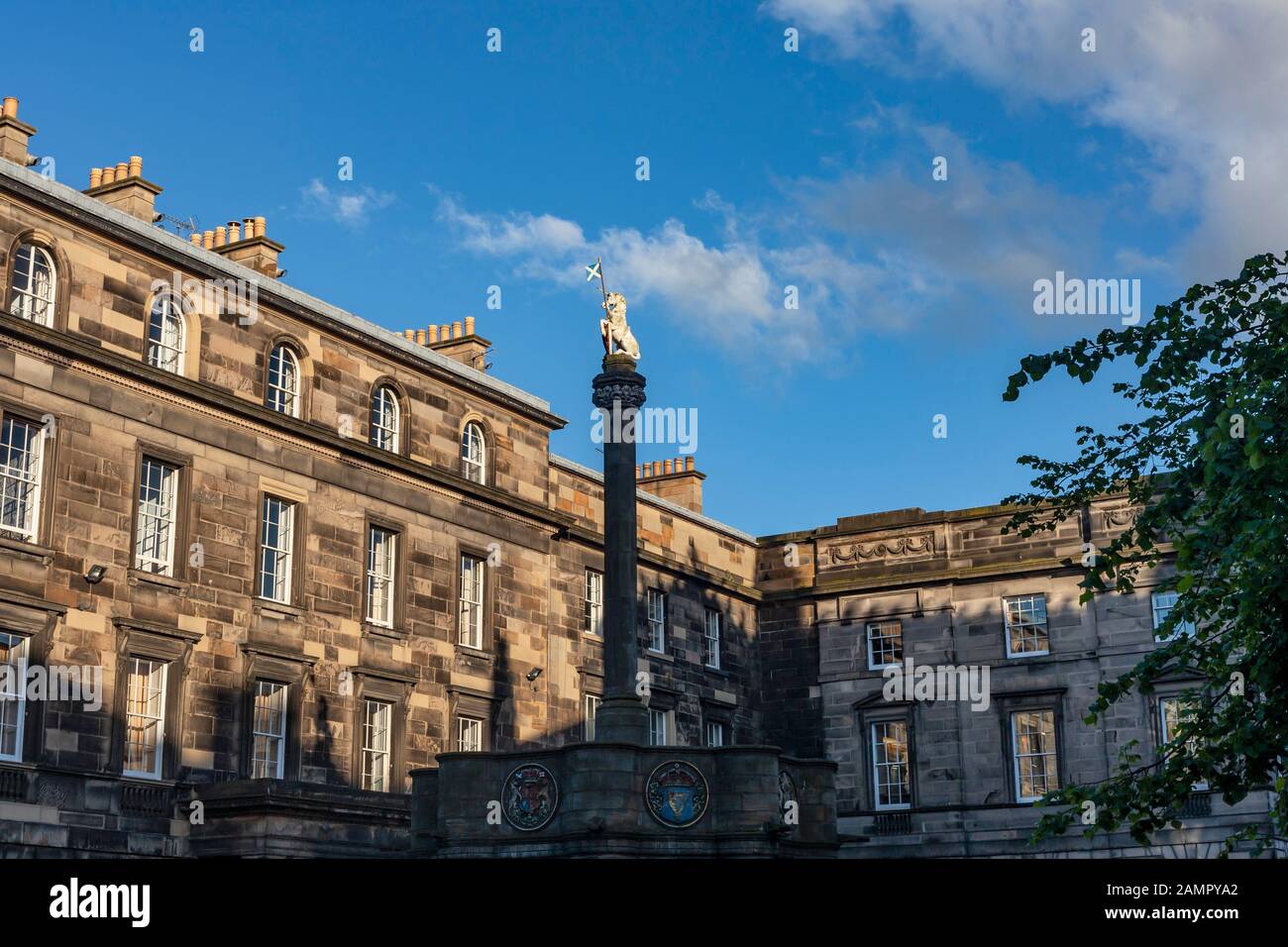 La statua di unicorno chiamato Mercat Cross con luce dorata brilla su di esso. L'Edinburgh City Chambers sono in background. Foto Stock