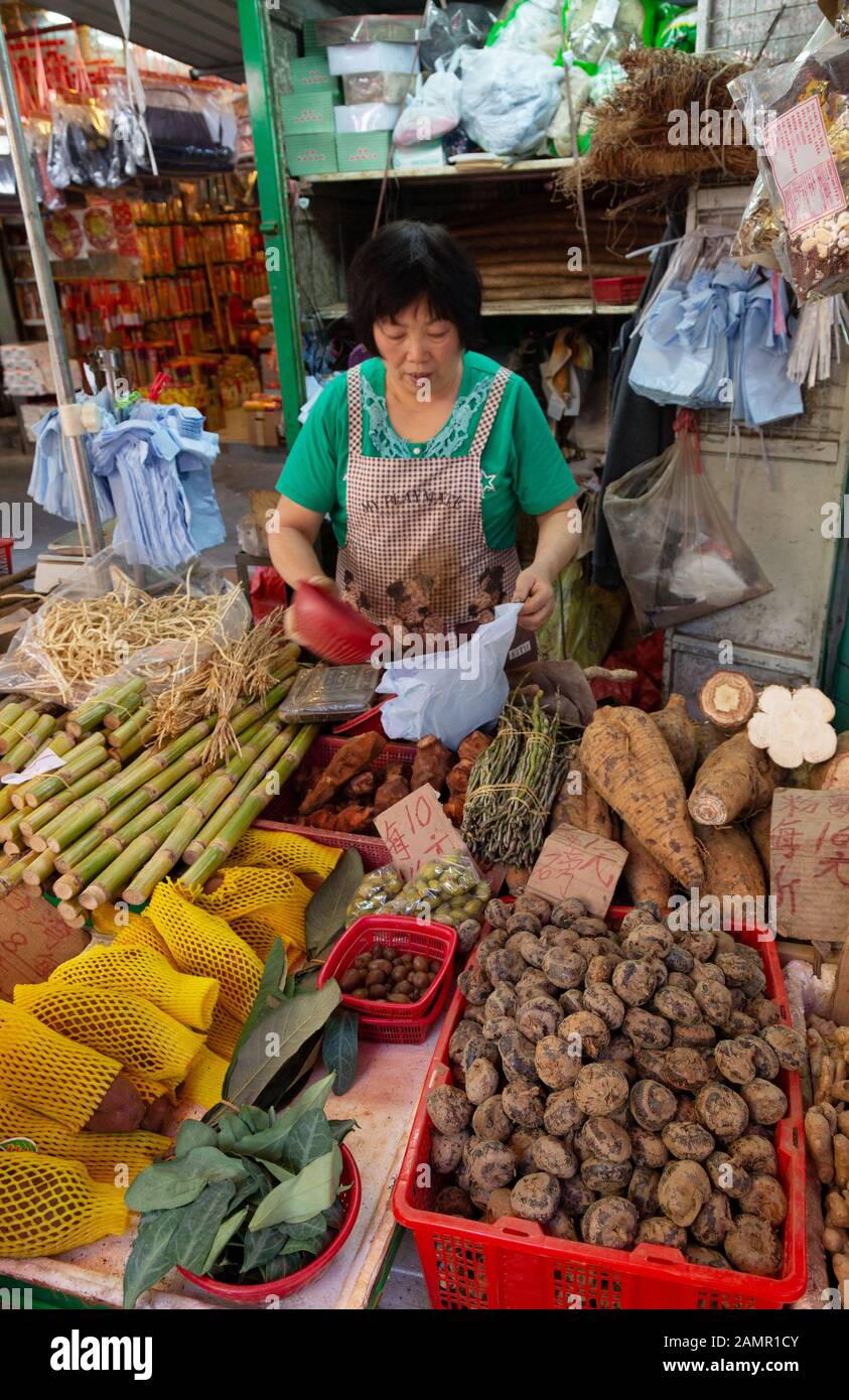 Donna asiatica commerciante di mercato che lavora alla sua stalla alimentare, il mercato alimentare, Bowring Street, Kowloon Hong Kong Asia, esempio di stile di vita asiatico Foto Stock