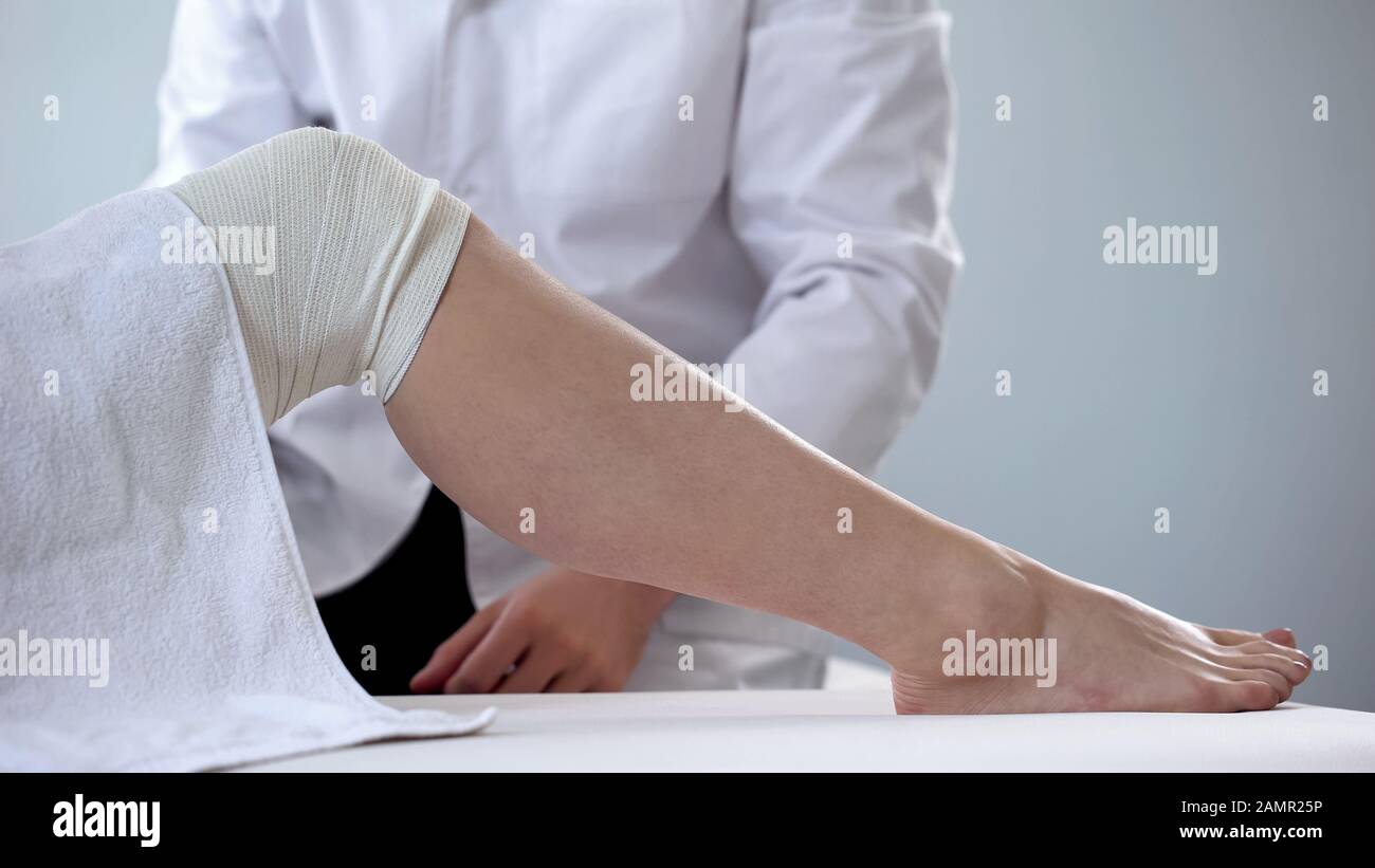 Medico che esamina le donne bendate gamba, varici venose, primo soccorso per le lesioni Foto Stock