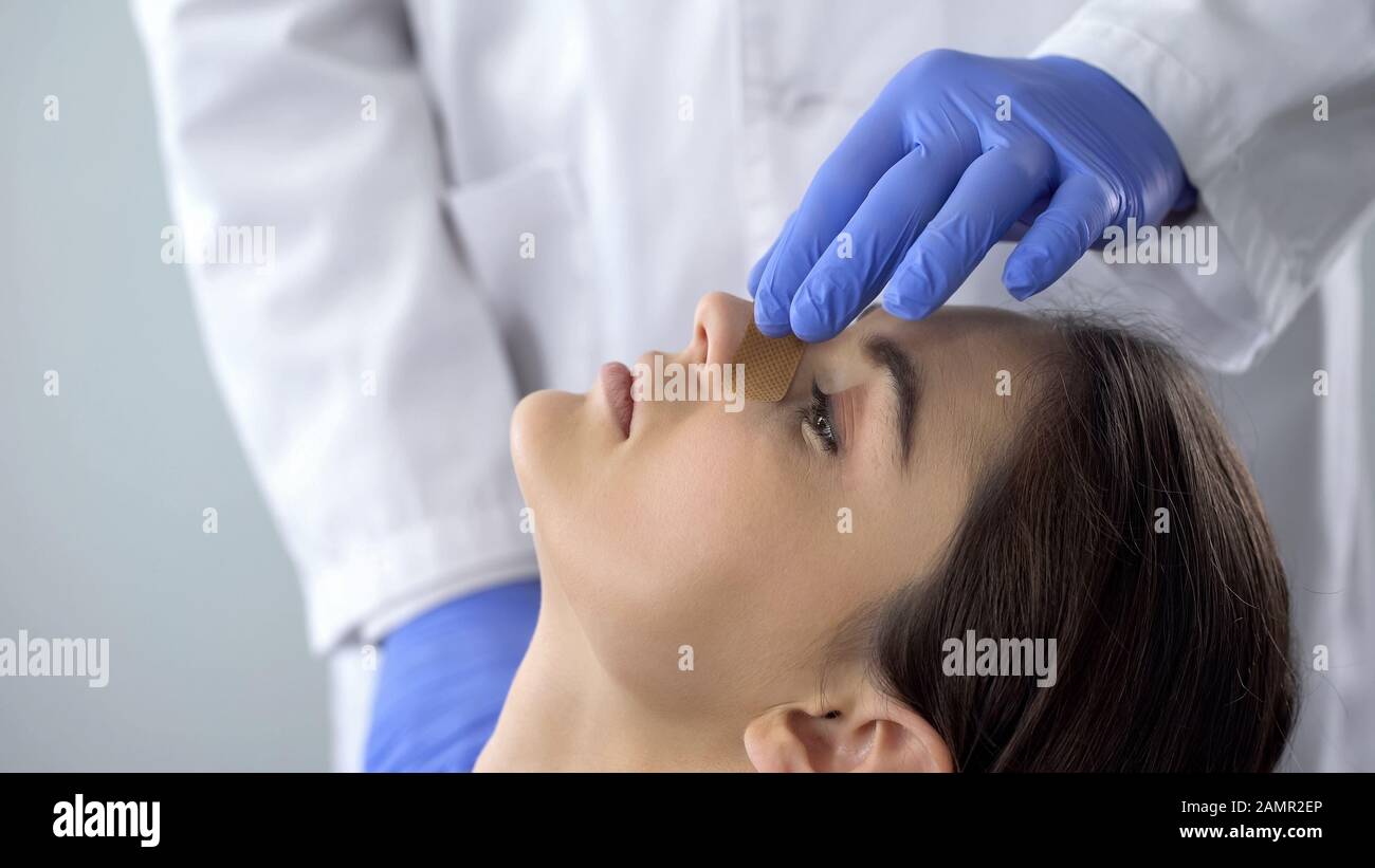 Medico che esamina il naso del paziente dopo la chirurgia di rinoplastica, l'aiuto medico, l'assistenza sanitaria Foto Stock