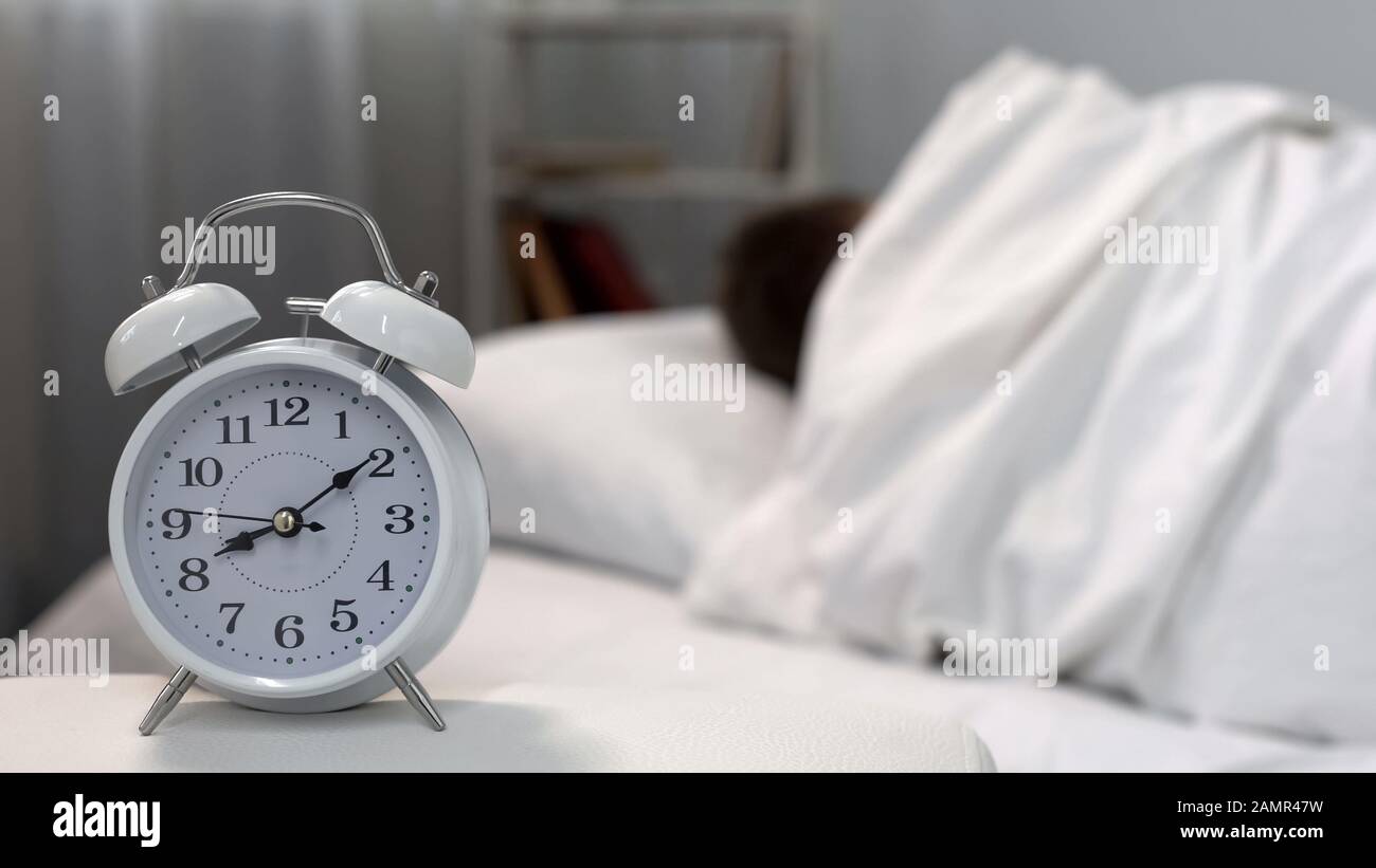 Sonno uomo ignorare l'orologio del letto al mattino, gestione del tempo, auto-disciplina Foto Stock
