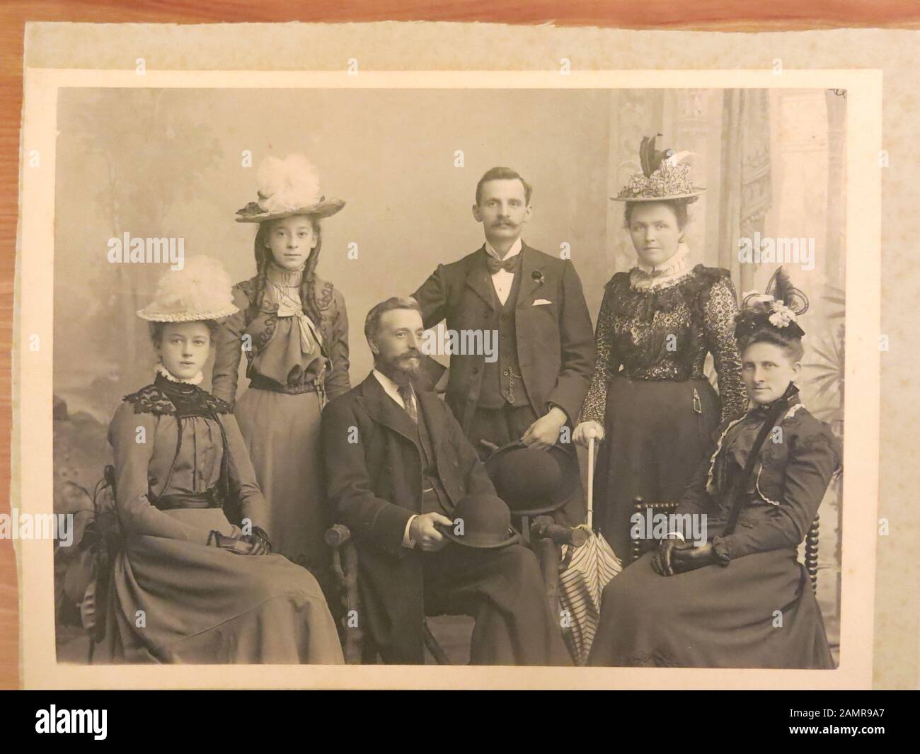 Copia di una vecchia foto b&w di un gruppo formale di 2 uomini e 4 donne in costume edoardiano e cappelli decorati, circa 1905. Foto Stock