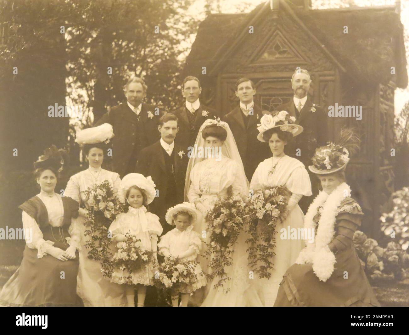 Foto seppia dal 1908 di un gruppo di famiglia in un quartiere alla moda di nozze con la sposa e lo sposo, e le donne in cappelli ornati e piuma boas. Foto Stock