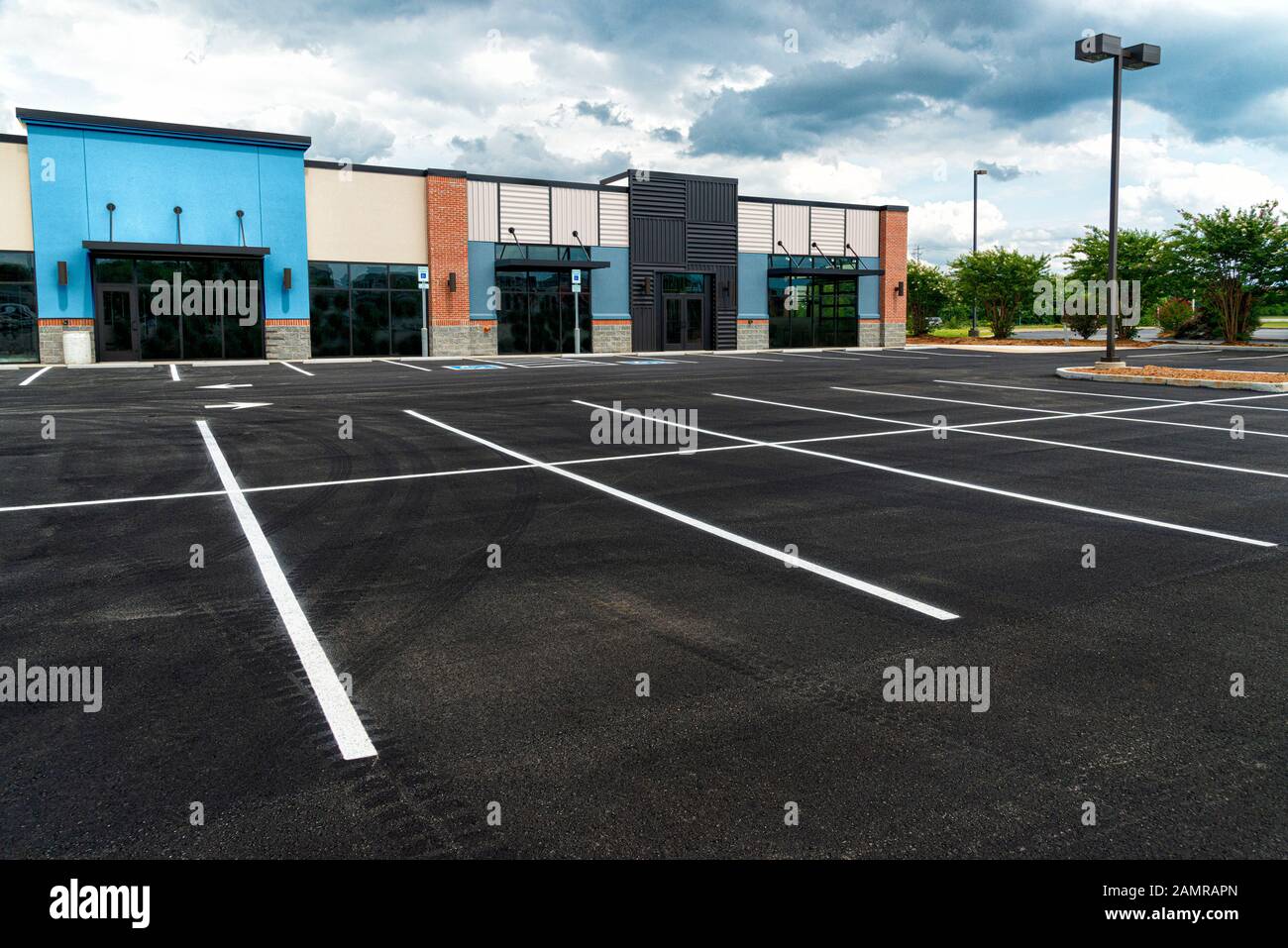 Scatto orizzontale di un nuovo centro commerciale della striscia senza clienti ed un parcheggio vuoto. Foto Stock