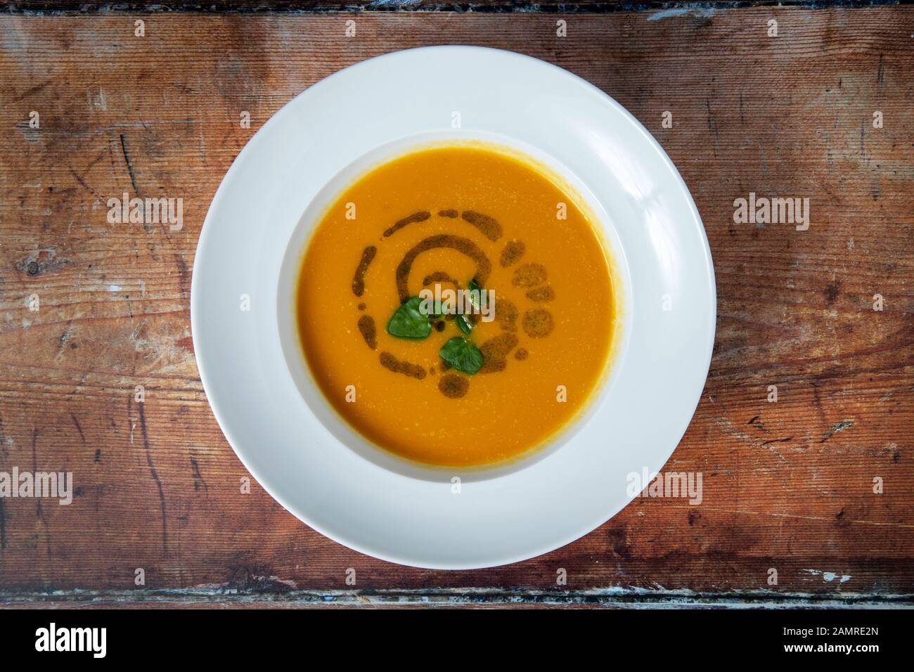 Arrosto di zucca zuppa di ortica e olio sul tavolato in legno sfondo Foto Stock