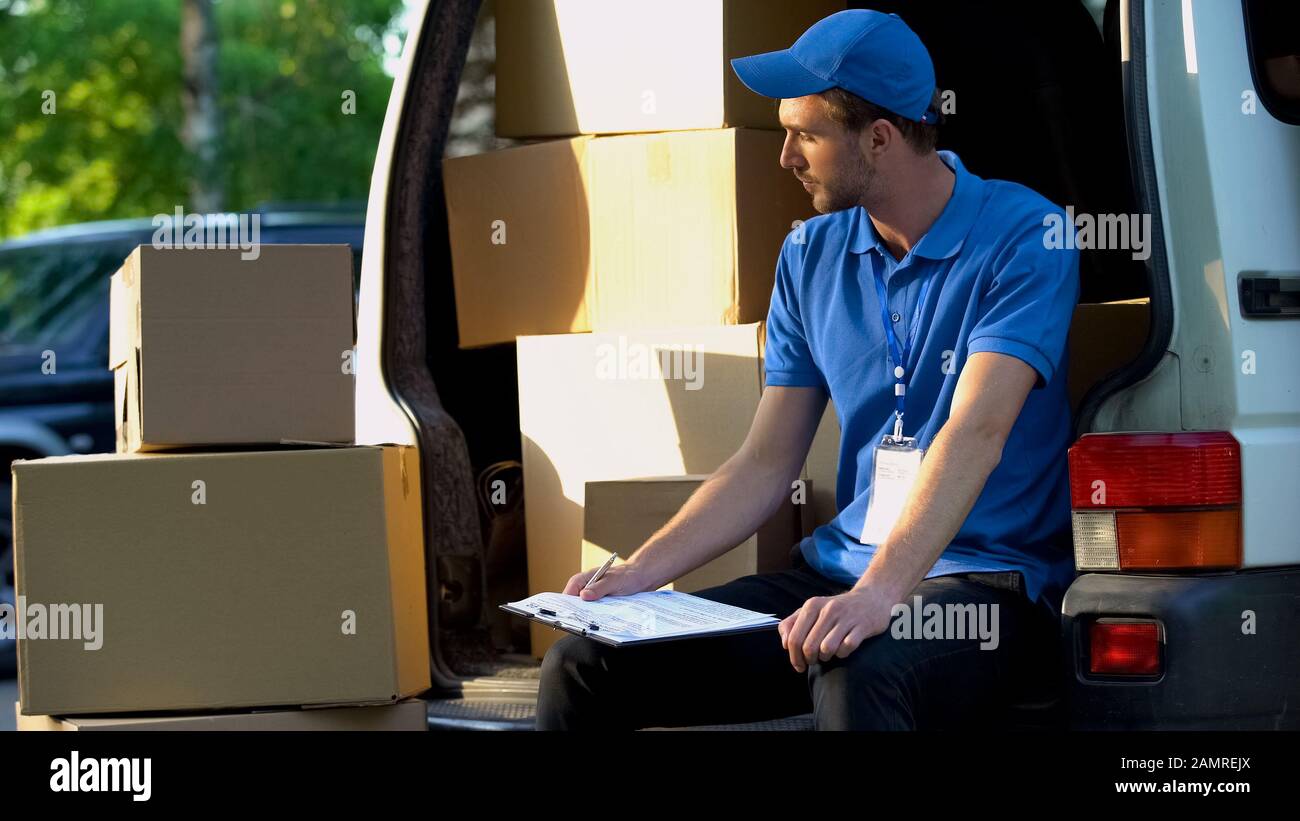 Lavoratore postale che riempie il rapporto di inventario, contando scatole di cartone, consegna Foto Stock