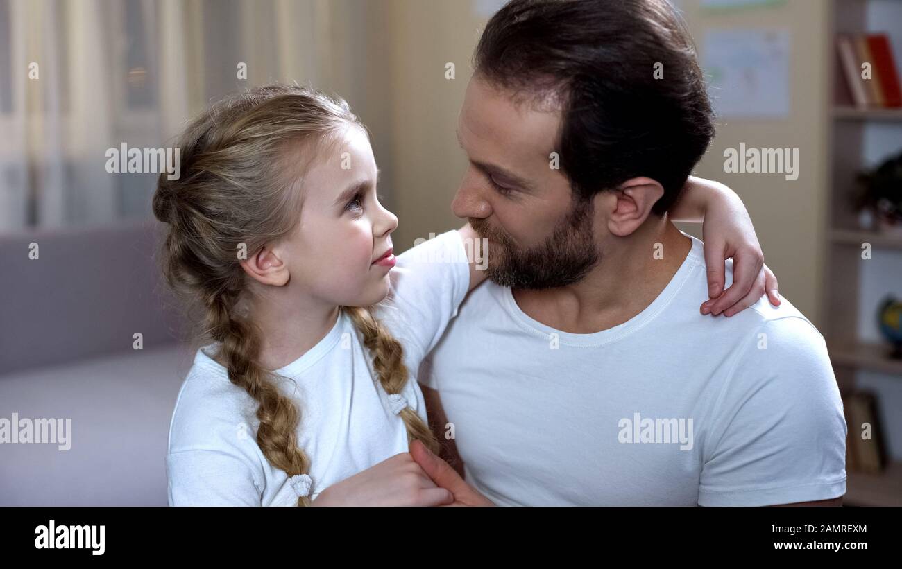 Il padre che si prende cura di cute figlia con amore e abbracciando, paternità felice Foto Stock