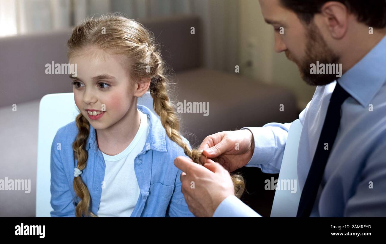 Singolo padre trecciare i capelli del bambino al mattino prima della scuola, del tempo della famiglia, della cura Foto Stock