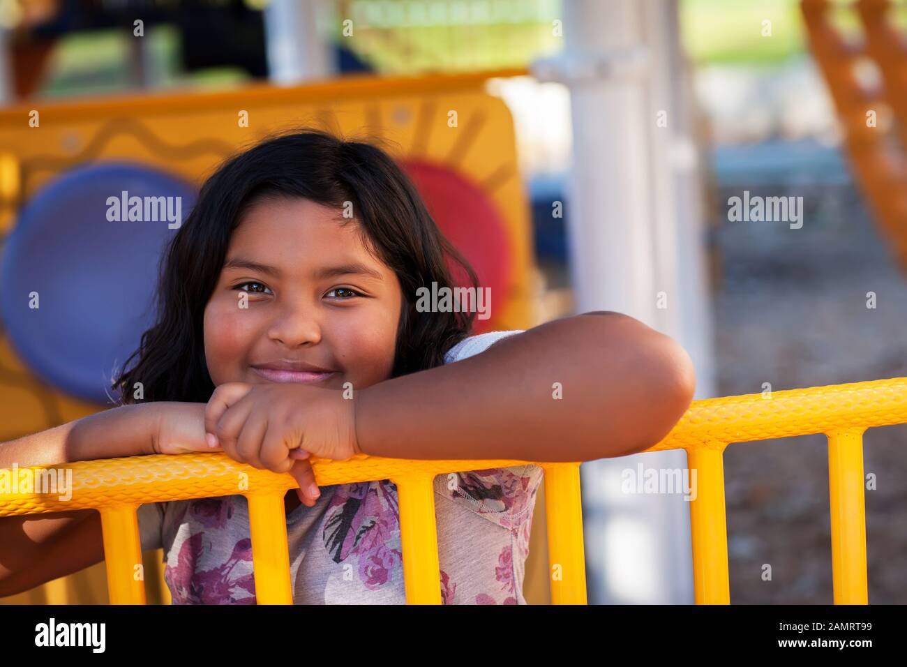 Una ragazza carino latino con un sorriso sincero che ha un grande tempo in un parco giochi per bambini. Foto Stock