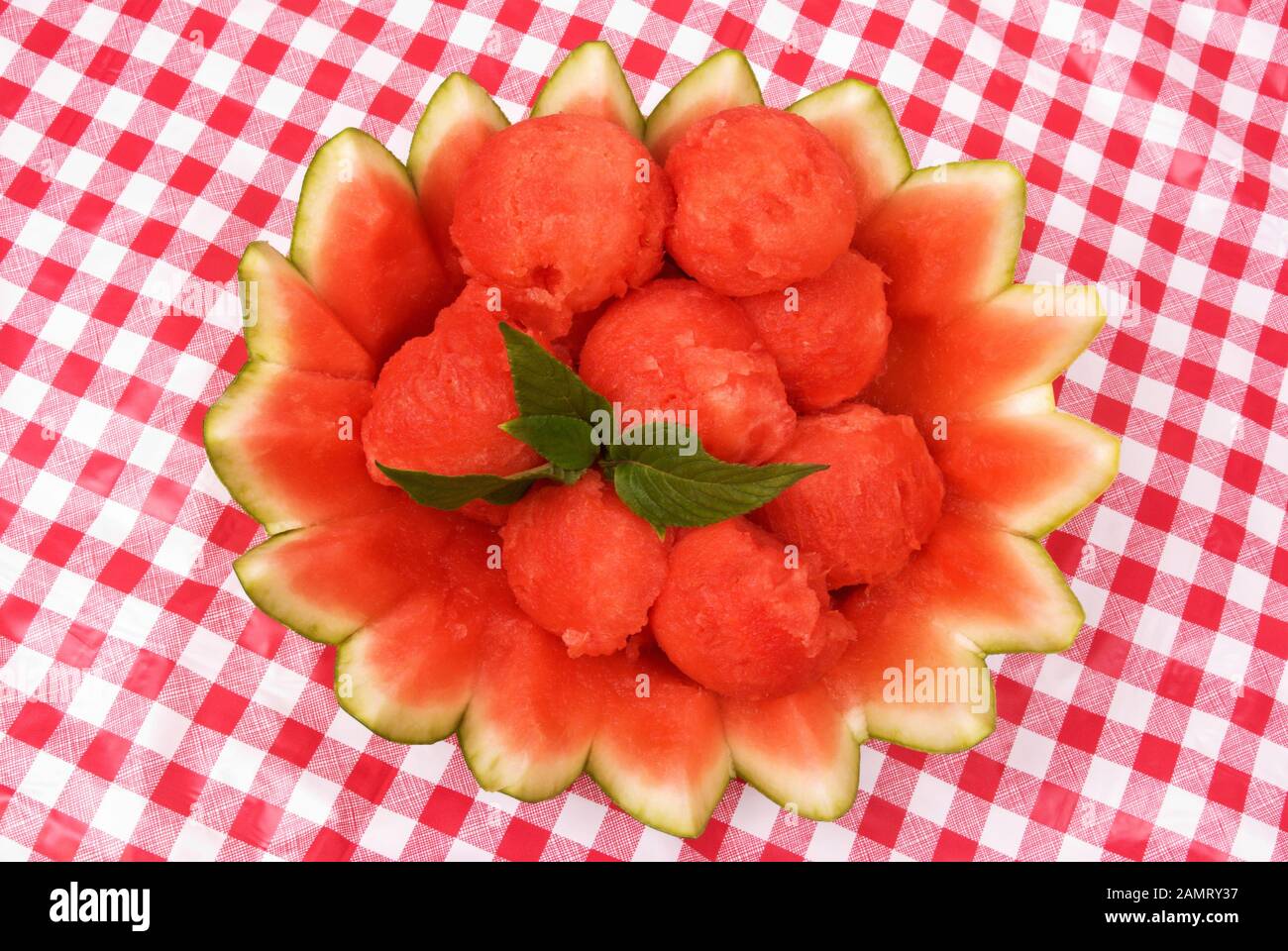 insalata di frutta al cocomero servita in una ciotola decorativa di cotenna al cocomero. Dolci foglie verdi di stevia è aggiunto per un garnizment. Foto Stock