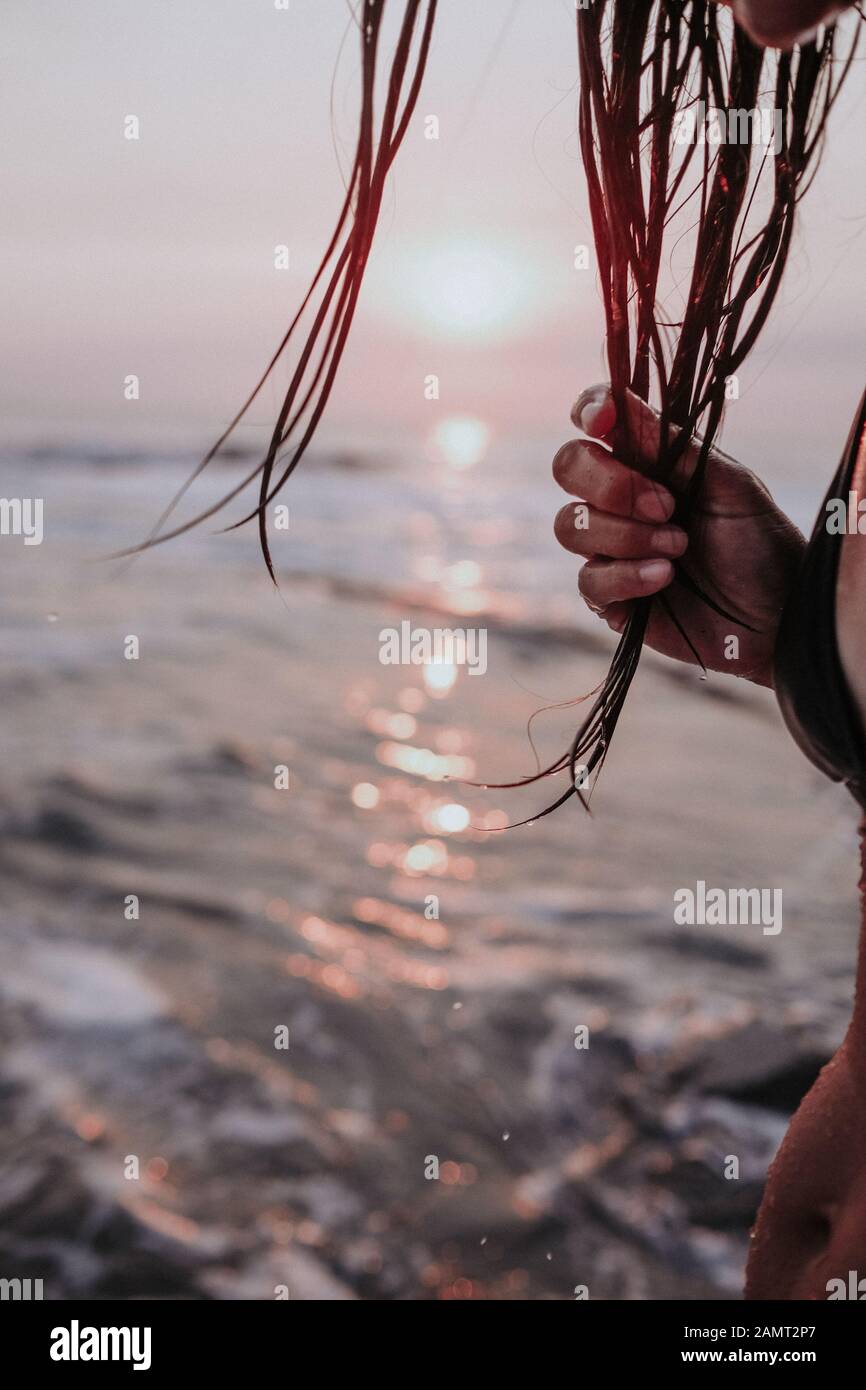 Primo piano di una donna sulla spiaggia con capelli bagnati al tramonto, Laguna Beach, California, Stati Uniti Foto Stock