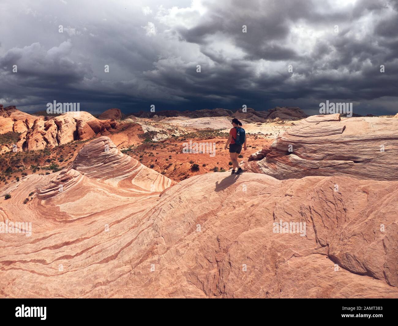 Donna escursioni in Valley of Fire state Park con tempesta in avvicinamento, Nevada, Stati Uniti Foto Stock