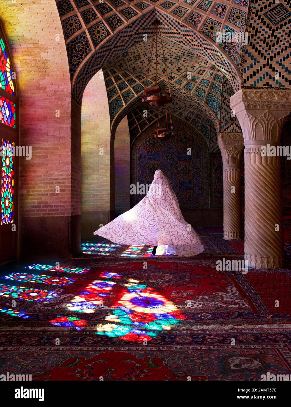 Donna che indossa un tradizionale abito iraniano a piedi attraverso la Moschea Rosa, Shiraz, Iran Foto Stock
