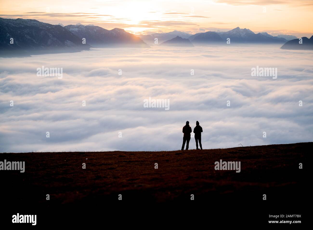 Silhouette di due donne su una cima di montagna al tramonto guardando la vista, Salisburgo, Austria Foto Stock