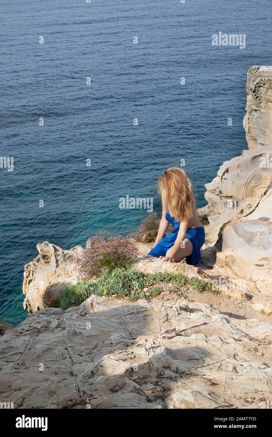 Donna inginocchiata su rocce di mare, Golfo di Baratti, Toscana, Italia Foto Stock