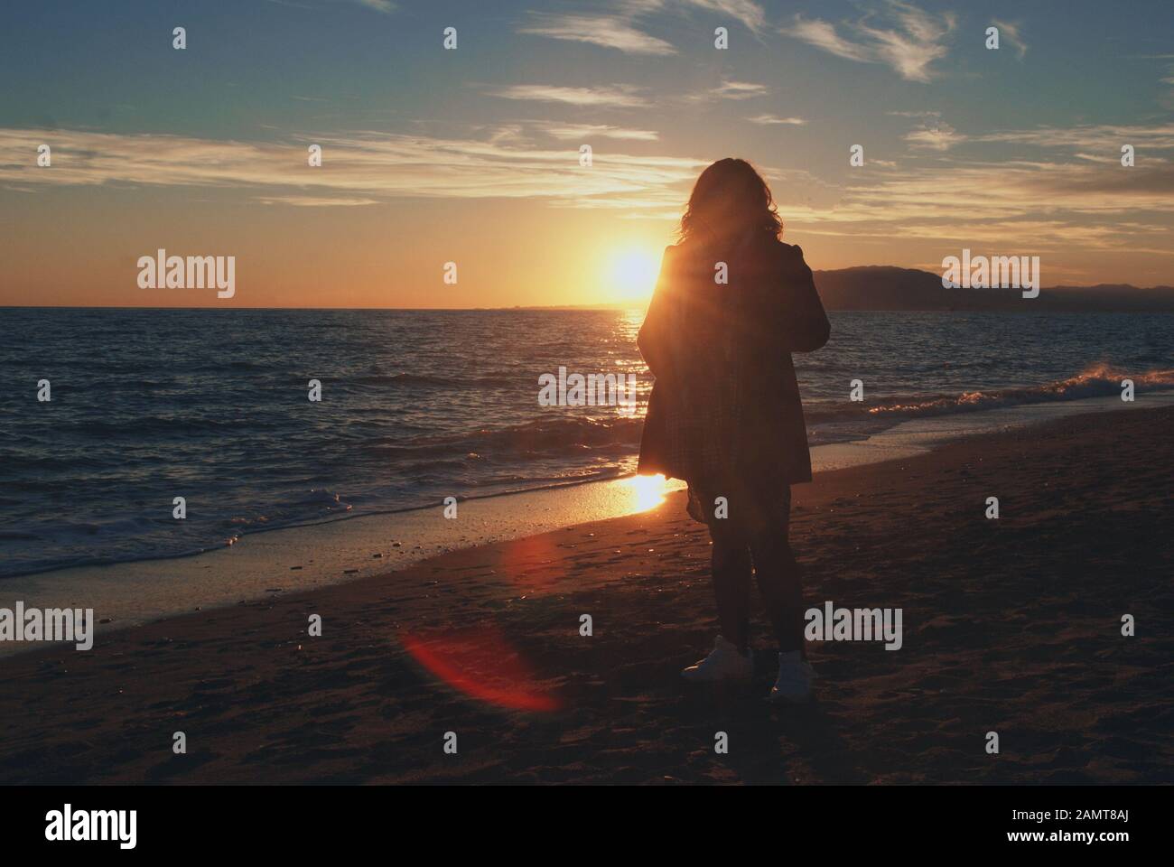 Silhouette di una donna che cammina sulla spiaggia al tramonto, Malaga, Spagna Foto Stock