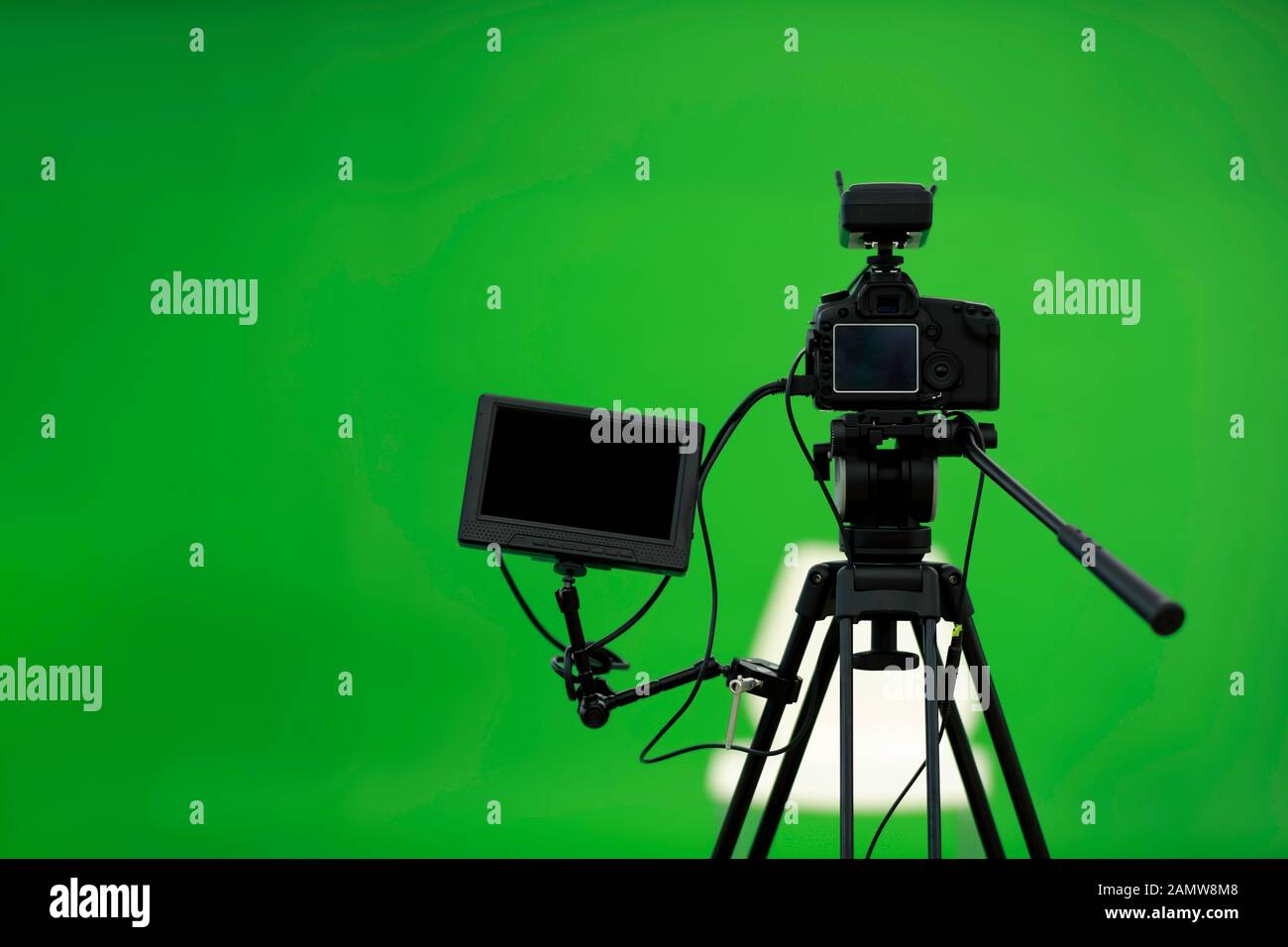 Fotocamera su treppiede collegata con monitor su sfondo verde. Foto Stock