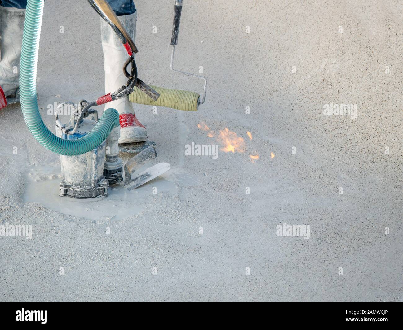 Uomo con un cannello al propano, rullo, e la coppa pompa durante una piscina ristrutturazione Foto Stock