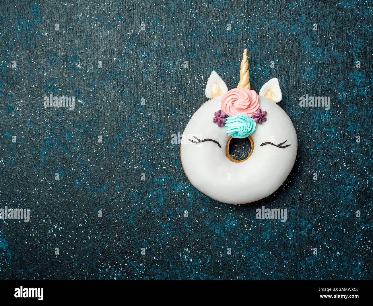 Unicorn ciambella su sfondo scuro. Ciambella alla moda unicorn con smalto bianco. Vista superiore piatta o laici. Copia spazio per il testo. Foto Stock