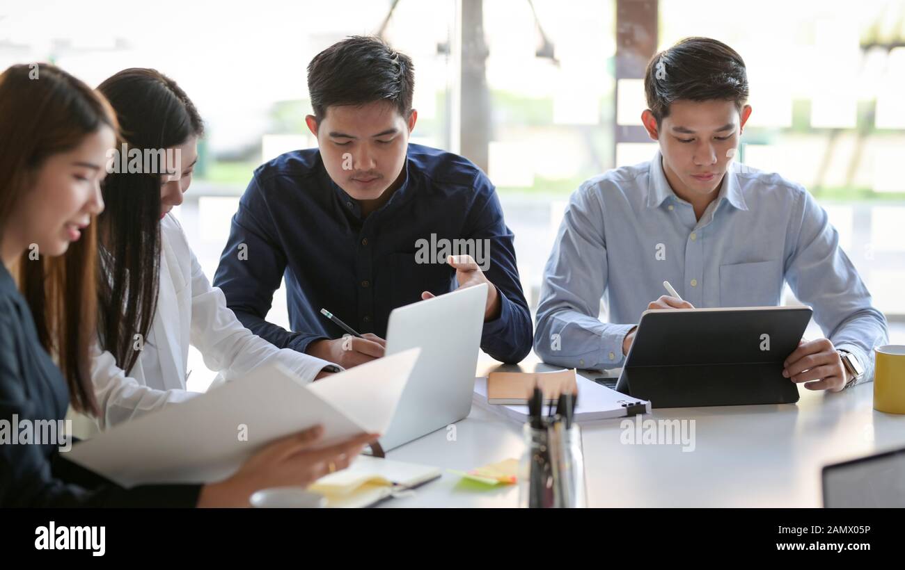 Tagliate il colpo di un gruppo di persone di business consulting il loro progetto in modo semplice sala riunioni Foto Stock