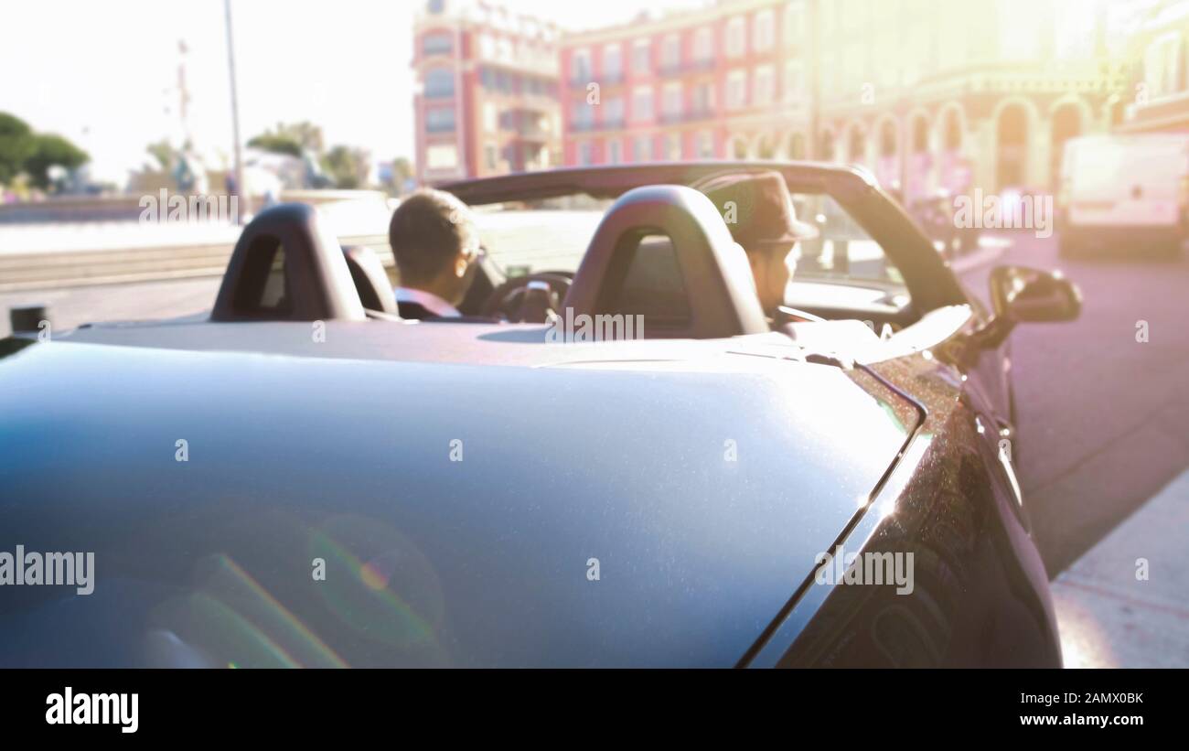 Elegante auto con tetto aperto lungo la strada vuota della città turistica, viaggio di lusso Foto Stock
