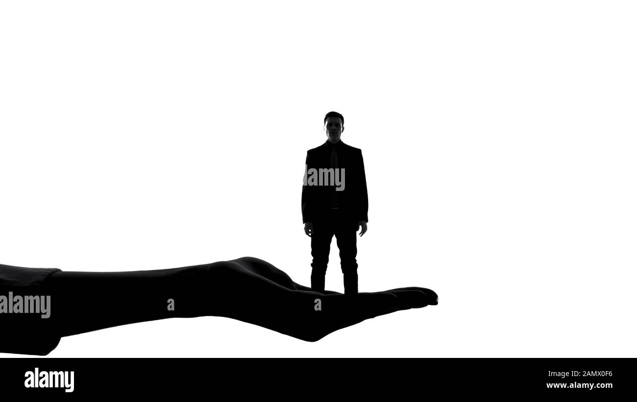 Silhouette di mano femminile che tiene l'uomo, autorità delle donne, manipolazione del dominio Foto Stock