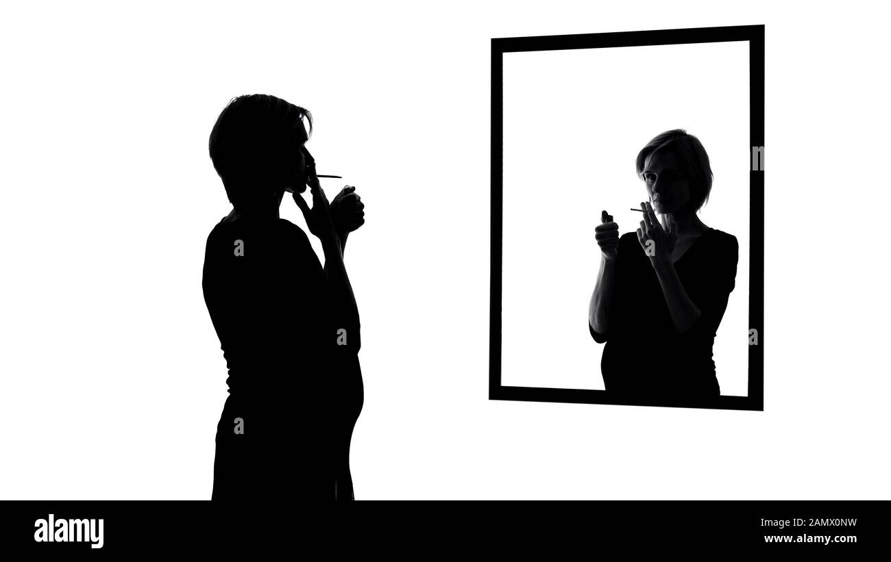 Donna incinta fumare sigaretta, guardare in specchio, coscienza chiedendo di smettere Foto Stock