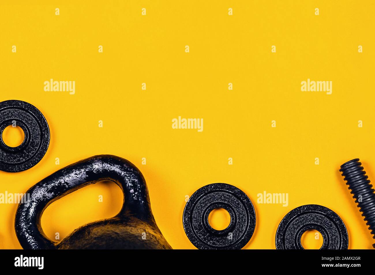 Sfondo di sport. Kettlebell e un manubrio su sfondo giallo. Appartamento laico, vista dall'alto, copia dello spazio. Foto Stock