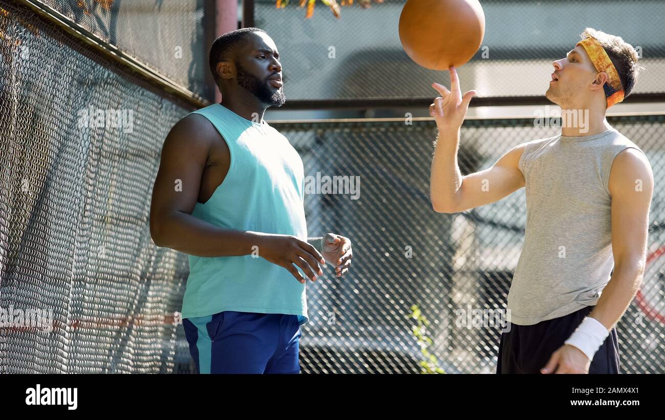 I compagni di gioco di basket comunicano, l'uomo che gira palla sul dito, gli amici Foto Stock