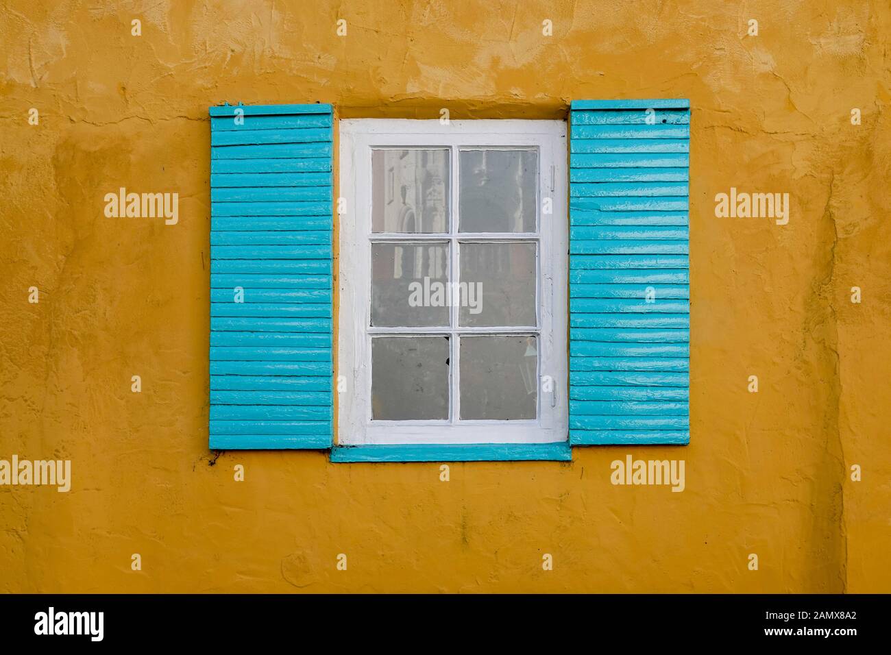 Parete gialla colorata e finestra con persiane blu Foto Stock