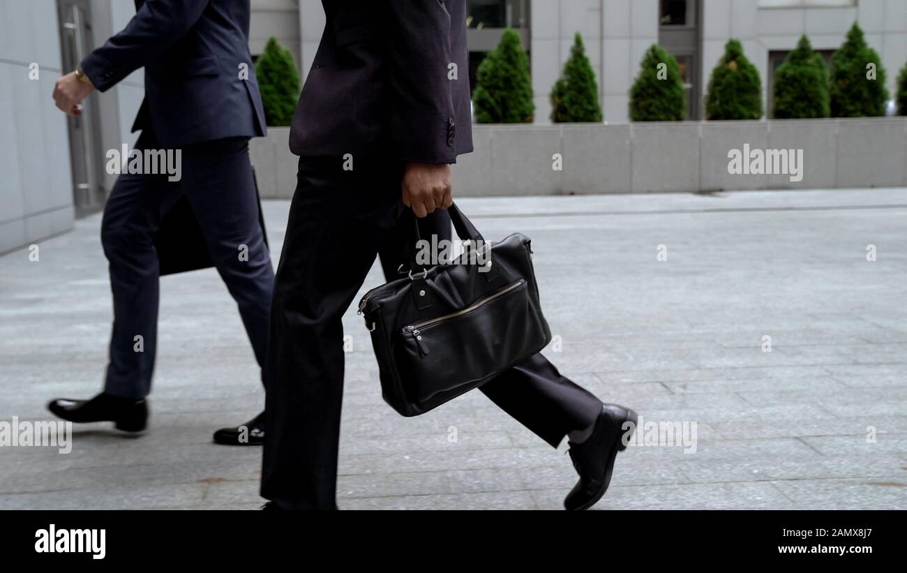 Gli impiegati si avvicinano alla costruzione dell'ufficio, portando le borse portadocumenti di cuoio, riunione Foto Stock