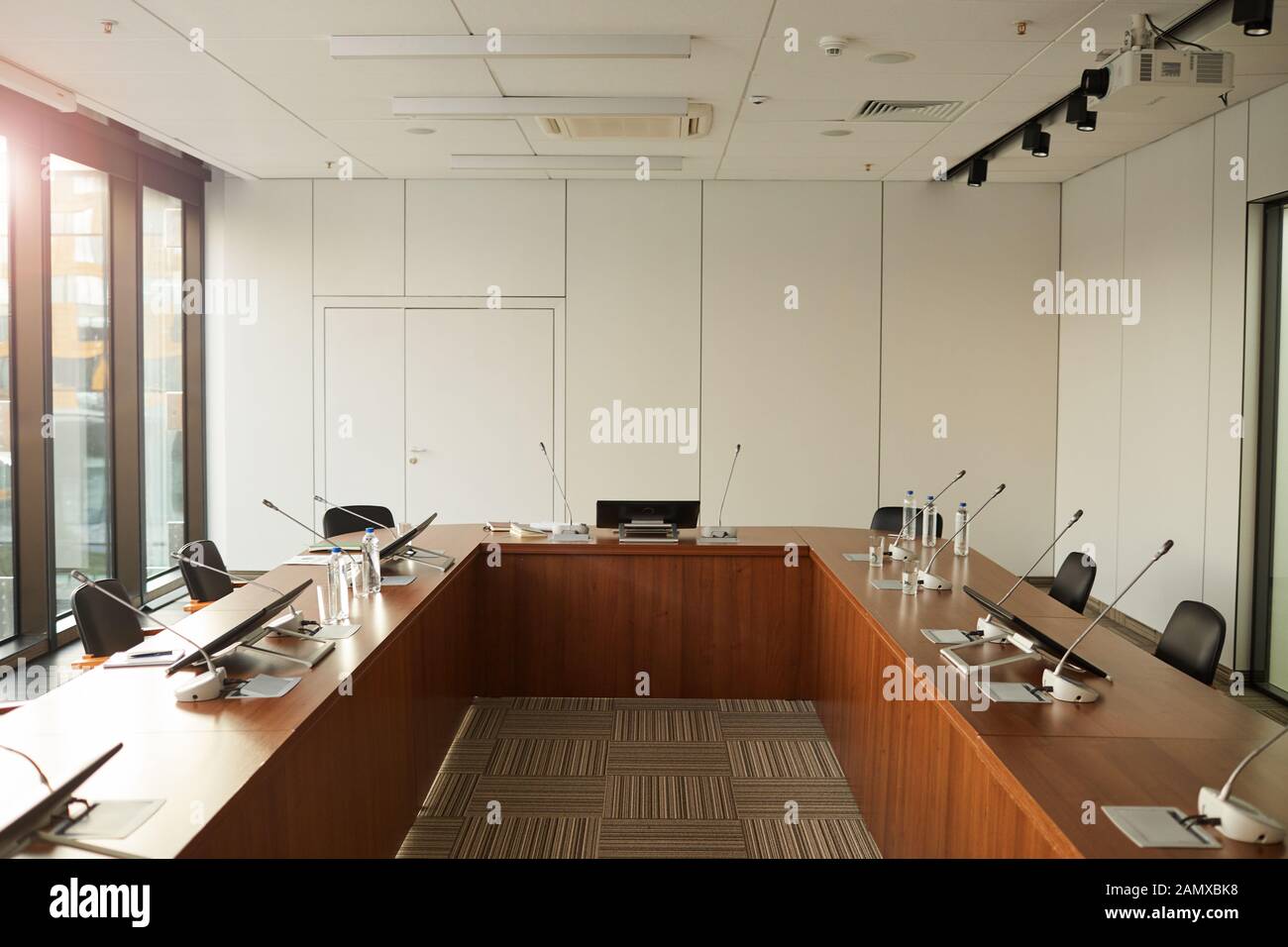 Immagine di un grande tavolo con monitor e microfoni per gli altoparlanti nella sala conferenze a edificio per uffici Foto Stock