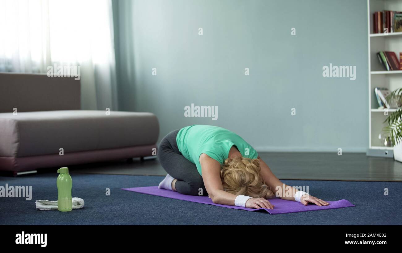 Donna atletica matura praticare yoga pone a casa, fitness e salute, stretching Foto Stock