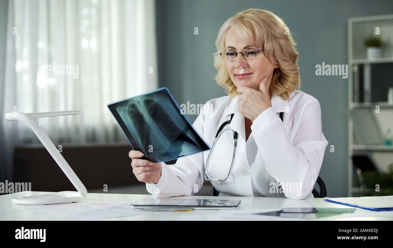 Radiologo femminile esperto che studia immagini radiografiche, diagnostica qualificata Foto Stock