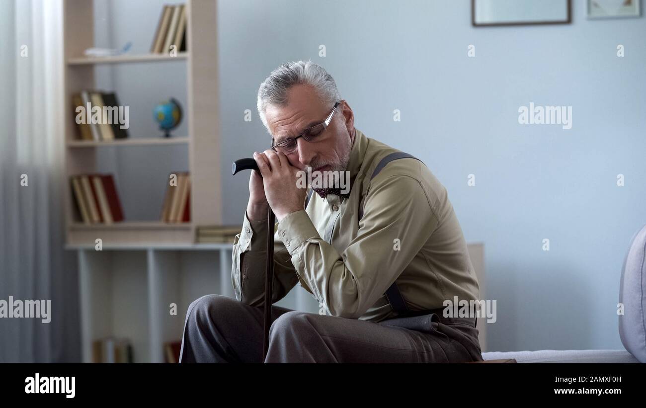 Uomo anziano appoggiato sul bastone da passeggio, che prende pisolino, il sonno pomeridiano buono per la salute Foto Stock