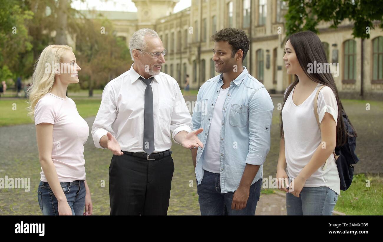 Insegnante di geografia senior che parla con gli studenti vicino all'università, spiegando l'argomento Foto Stock