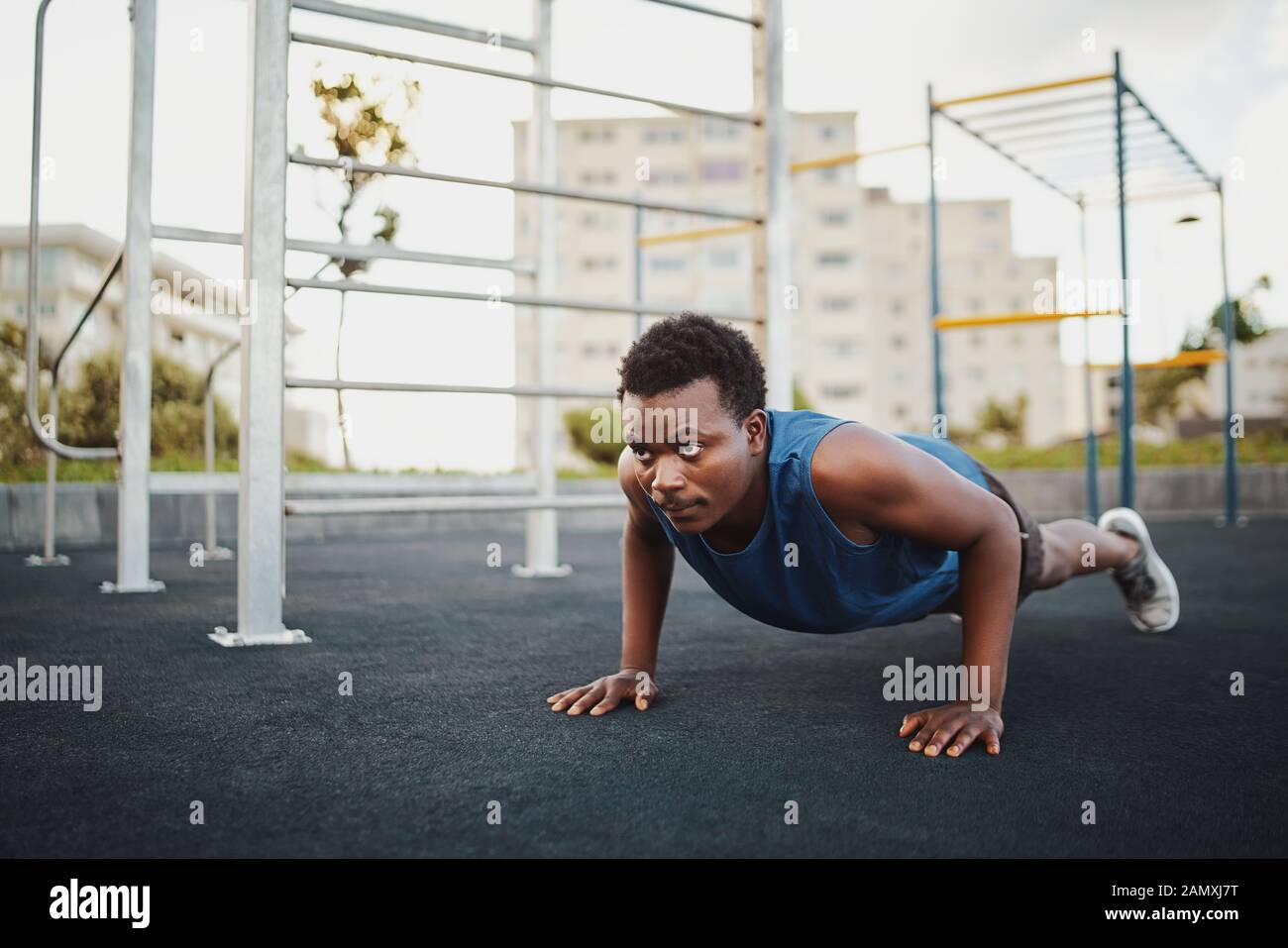 Montare il giovane americano africano uomo al lavoro su crossfit training di forza facendo spingere ups al parco calisthenics Foto Stock
