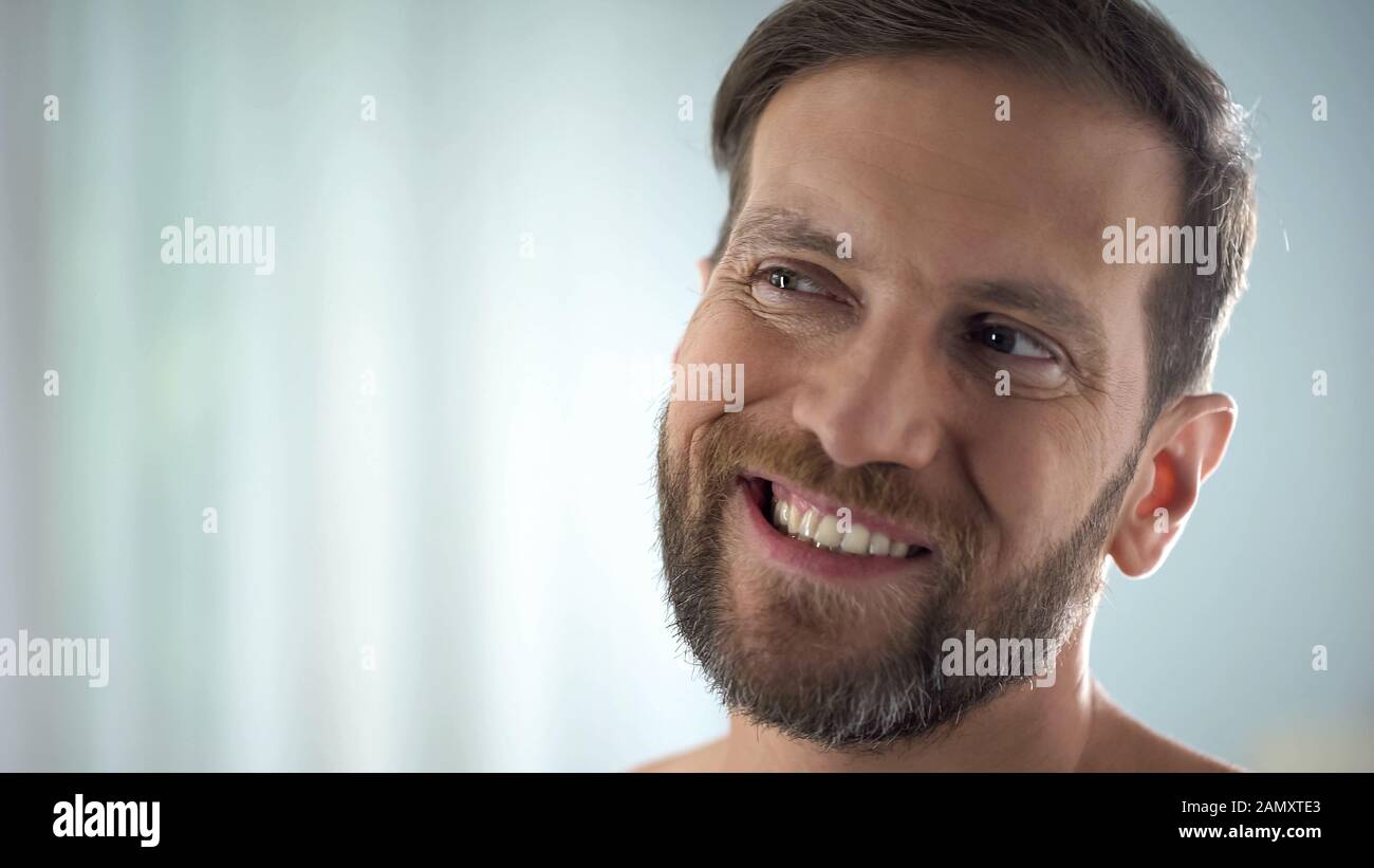 Uomo di mezza età che controlla i denti davanti allo specchio, malattia dentale, infezione delle gengive Foto Stock
