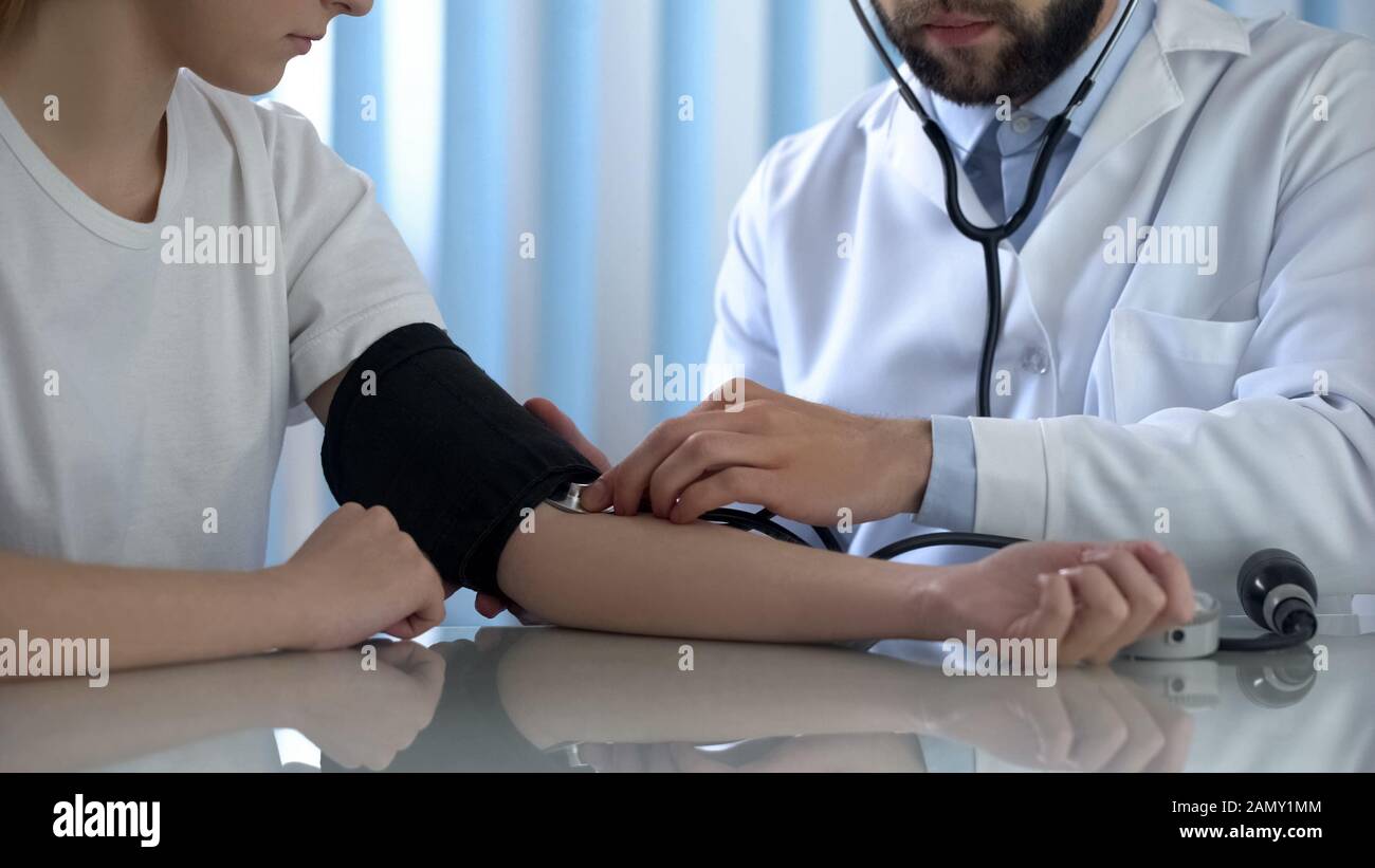 Medico professionista che misura la pressione sanguigna di giovane donna, salute e medicina Foto Stock