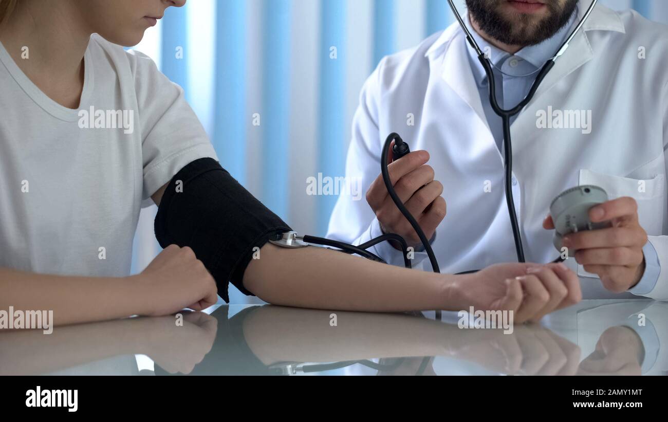 Il medico sta guardando sui risultati della misurazione della pressione sanguigna del paziente, l'assistenza sanitaria Foto Stock