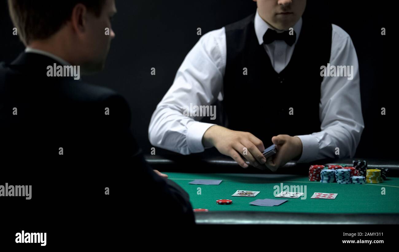 Croupier di casino maschio che si occupano di carte per l'uomo d'affari, la possibilità di vincere al gioco di poker Foto Stock