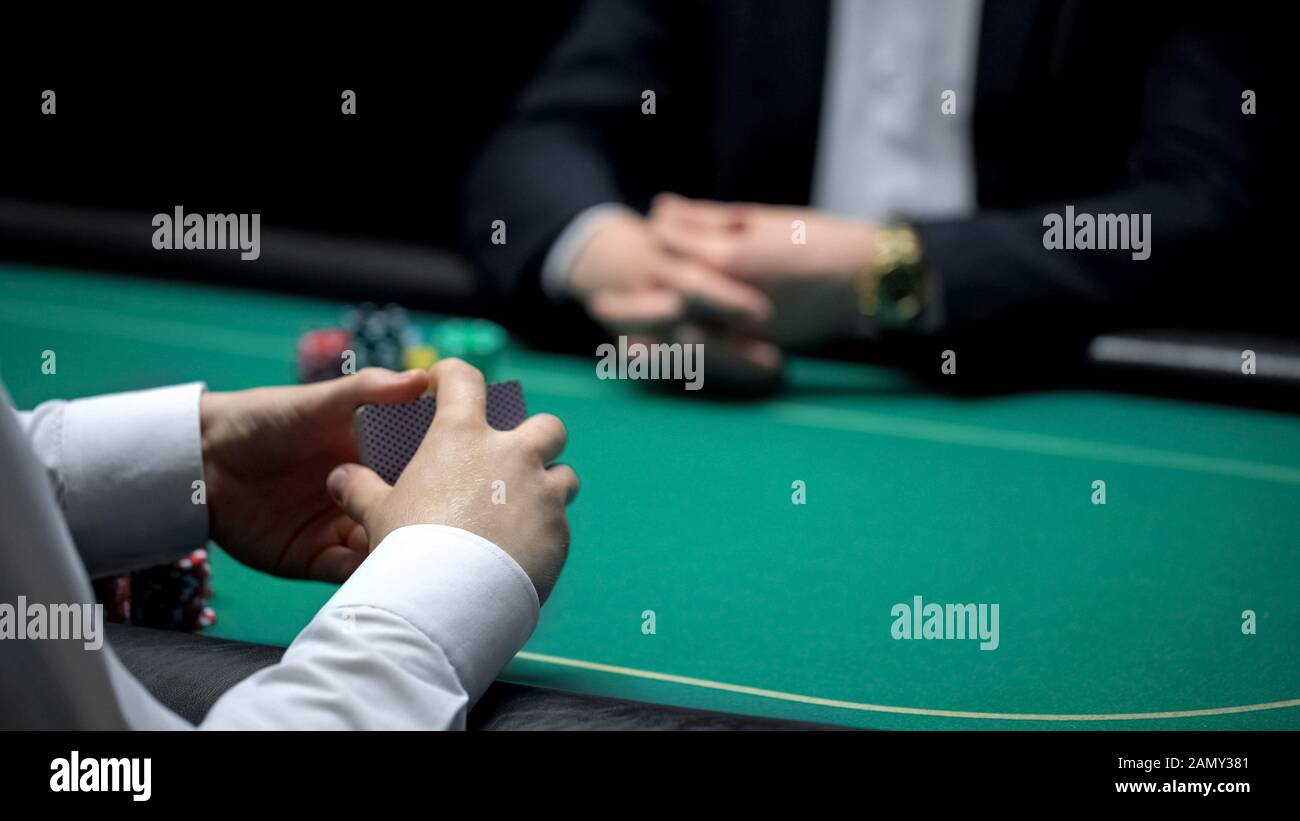 Croupier maschio shuffling carte al casinò, pronto per iniziare il gioco di poker con il cliente Foto Stock