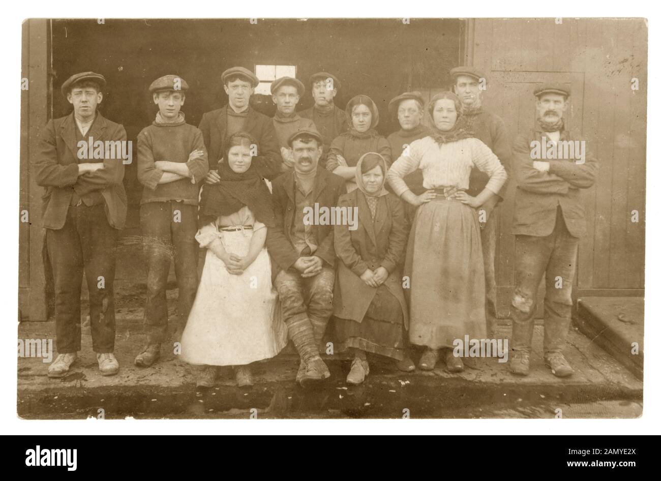 Edwardian fotografia di gruppo di giovani ragazze e ragazzi con gli uomini  più anziani, eventualmente sorveglianti,vestito in abiti da lavoro -  zoccoli, scialli. Questi sono probabilmente i lavoratori del mulino come una