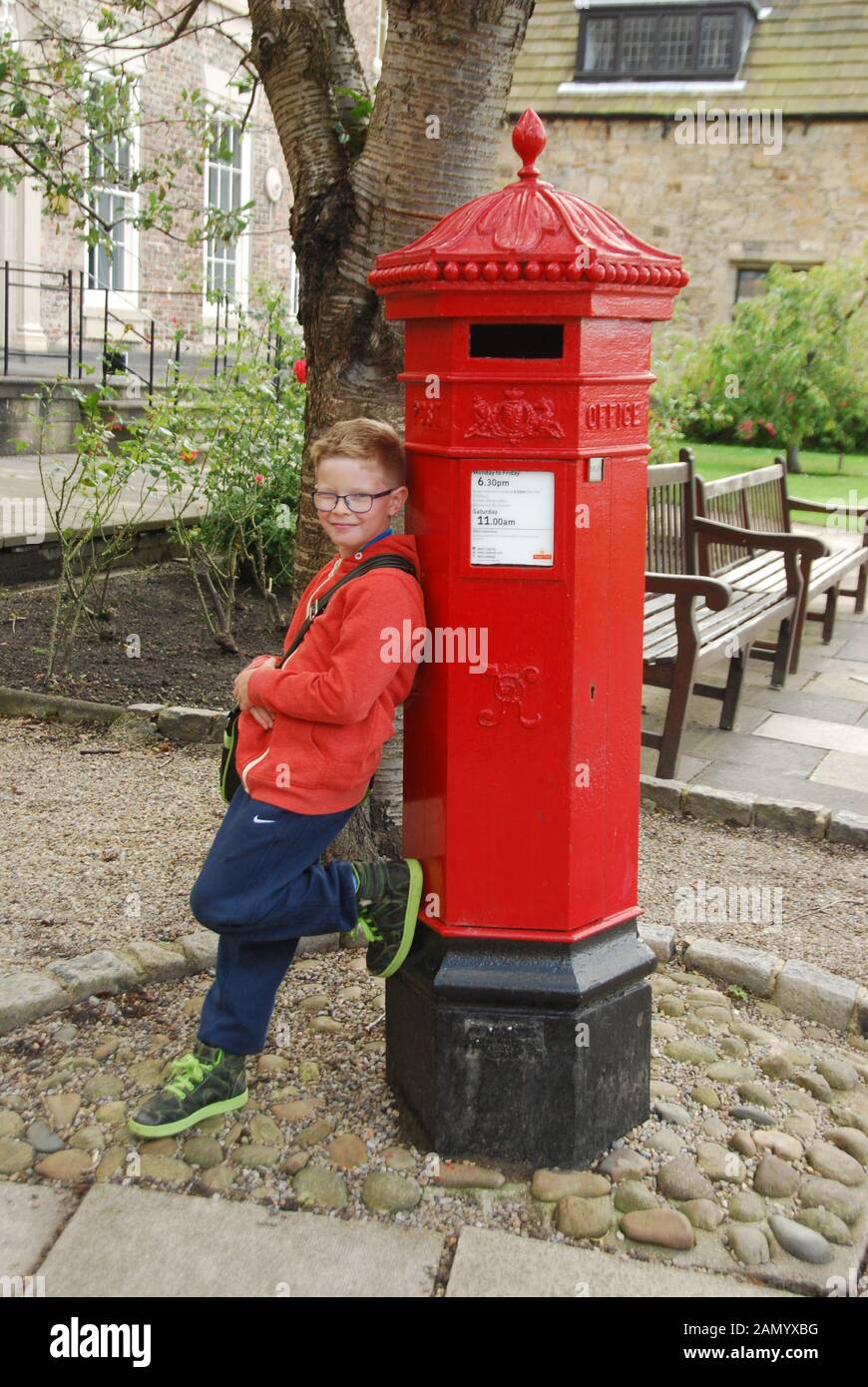 Rosso pilastro Vittoriano Box presso la Cattedrale di Durham County Durham Regno Unito con un giovane ragazzo in parte superiore rossa appoggiata contro la scatola del montante Foto Stock