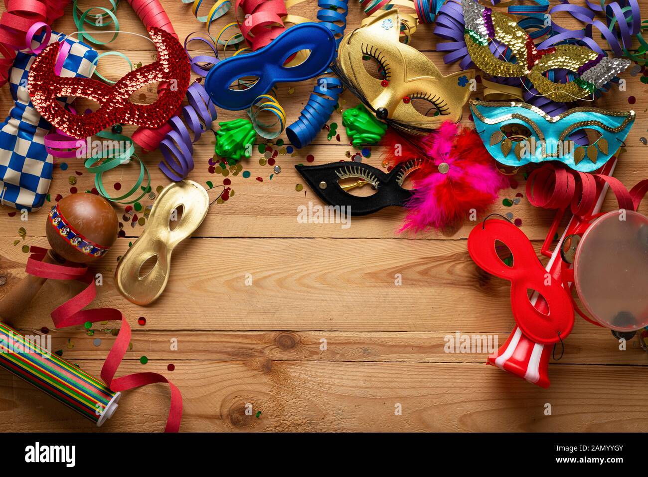 Il carnevale sfondo su una superficie in legno. Le maschere, spiralato stelle filanti e coriandoli e molti altri Foto Stock